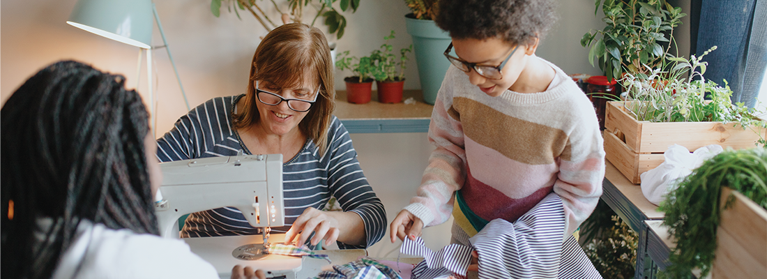 Image of a grandparent teaching their grandchildren how to sew clothing